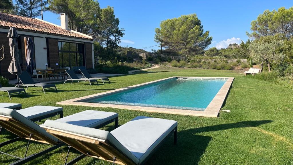 um quintal com uma piscina e cadeiras e uma casa em La Bergerie du Roy-Chambres D'hôtes- em Rognes