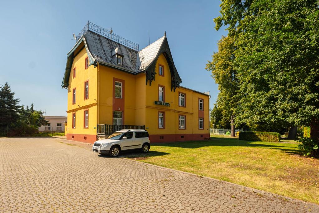 um pequeno carro estacionado em frente a um edifício amarelo em Hotel Orka em Moravská Trebová