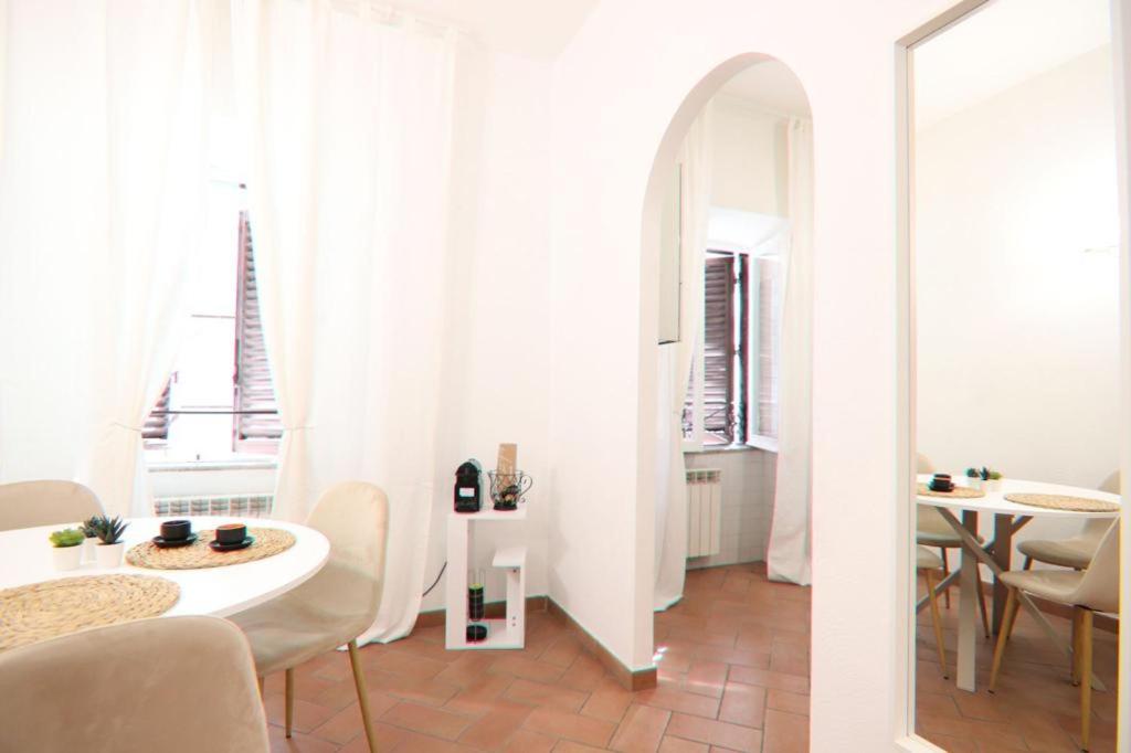 Biały pokój ze stołem i krzesłami oraz oknem w obiekcie Colosseum 20 apartment w Rzymie