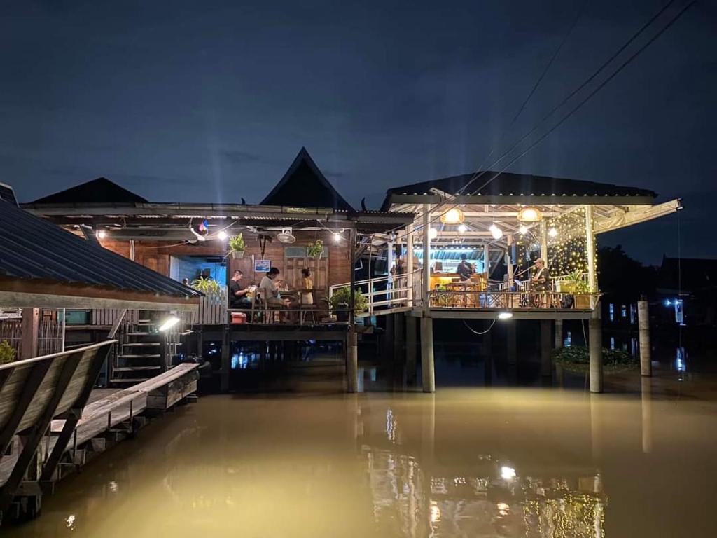 a seafood restaurant on the water at night at Popole in Nonthaburi