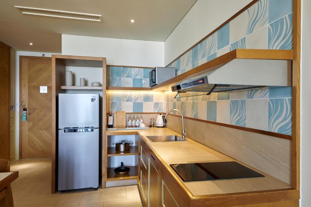 a kitchen with a stainless steel refrigerator and wooden cabinets at Fusion Suites Vung Tau in Vung Tau