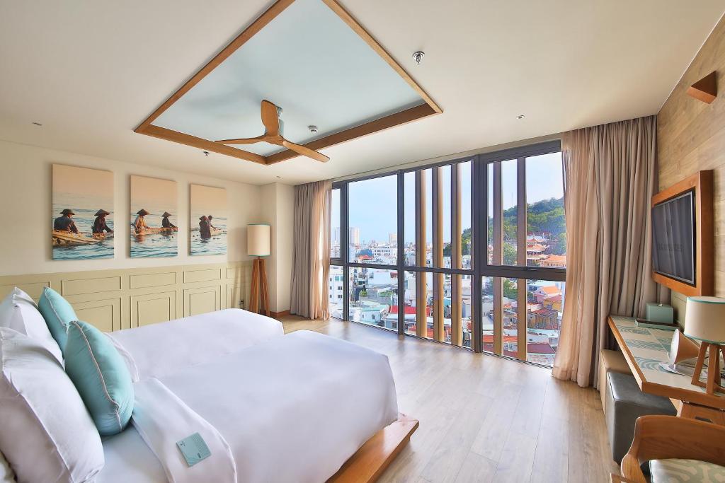 a bedroom with a large bed and a large window at Fusion Suites Vung Tau in Vung Tau