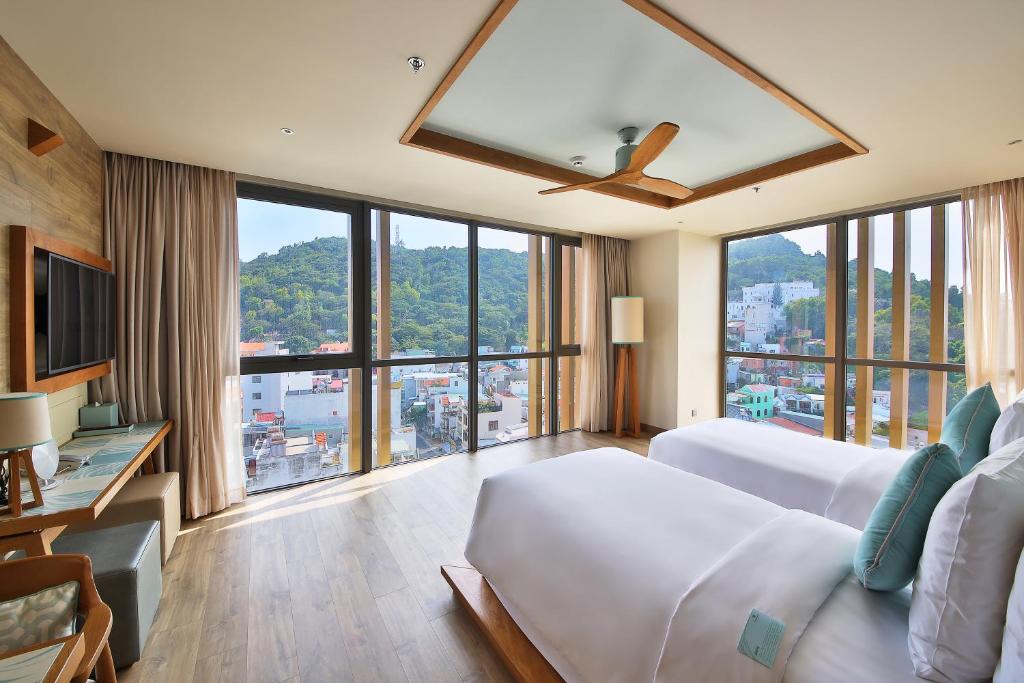 a hotel room with a bed and a large window at Fusion Suites Vung Tau in Vung Tau