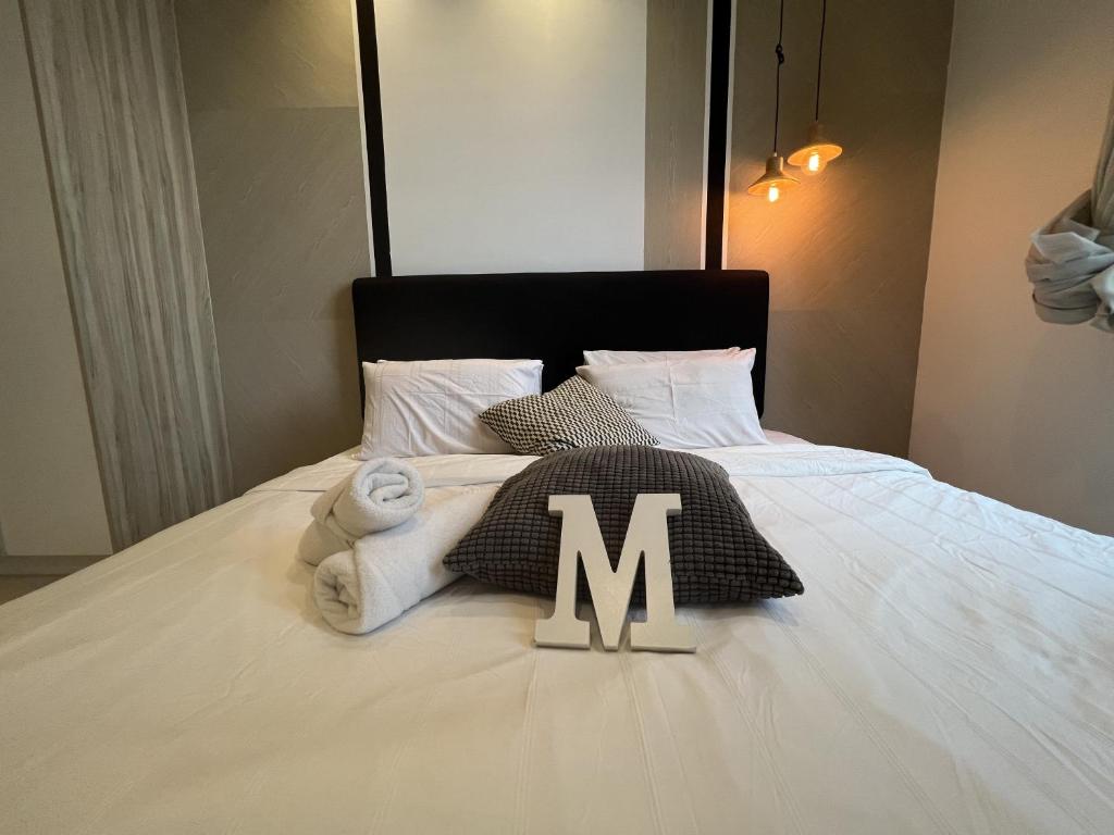 a pile of towels with the letter m on a bed at ARCORIS, MONT KIARA by MK HOME in Kuala Lumpur