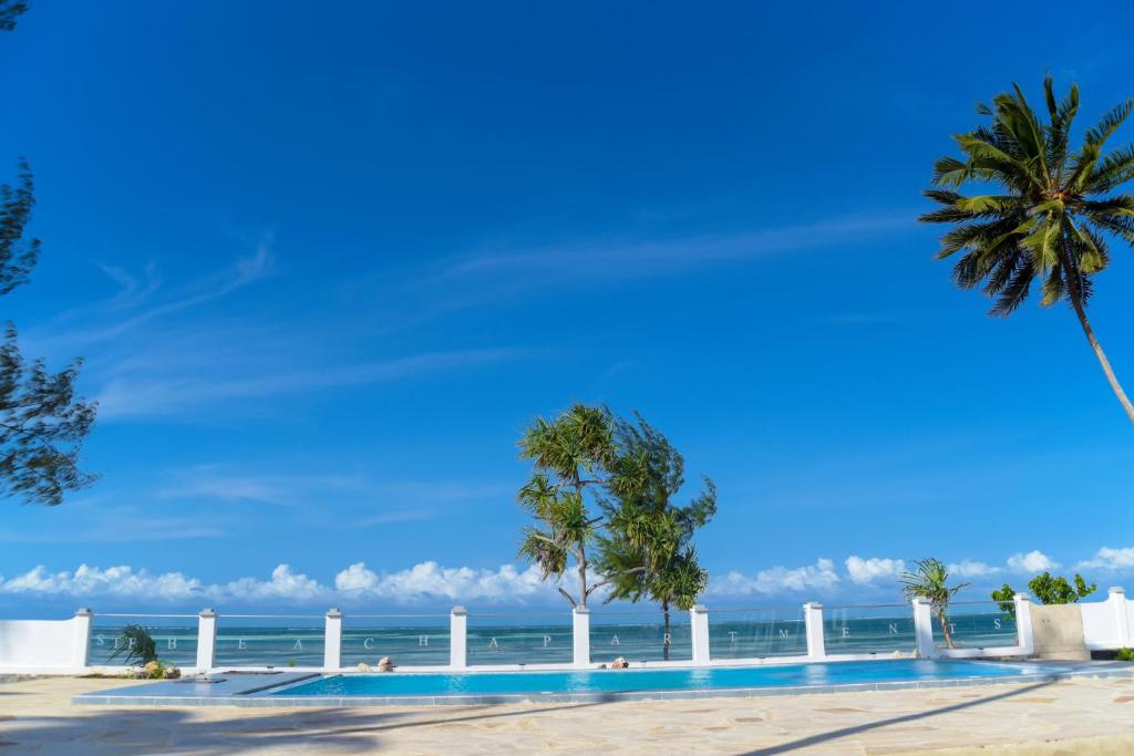 - une piscine sur la plage avec des palmiers et l'océan dans l'établissement Kiwengwa Minazi Resort, à Kiwengwa