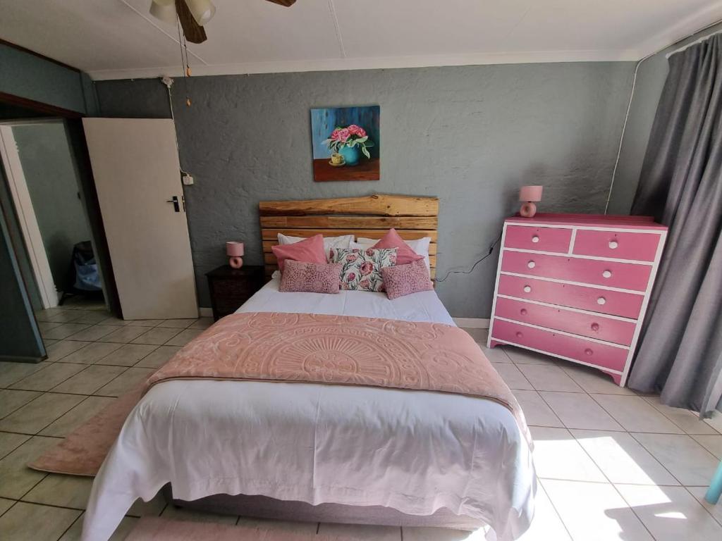 a bedroom with a large bed and a pink dresser at Abaloo Apartment #1 in Sabie