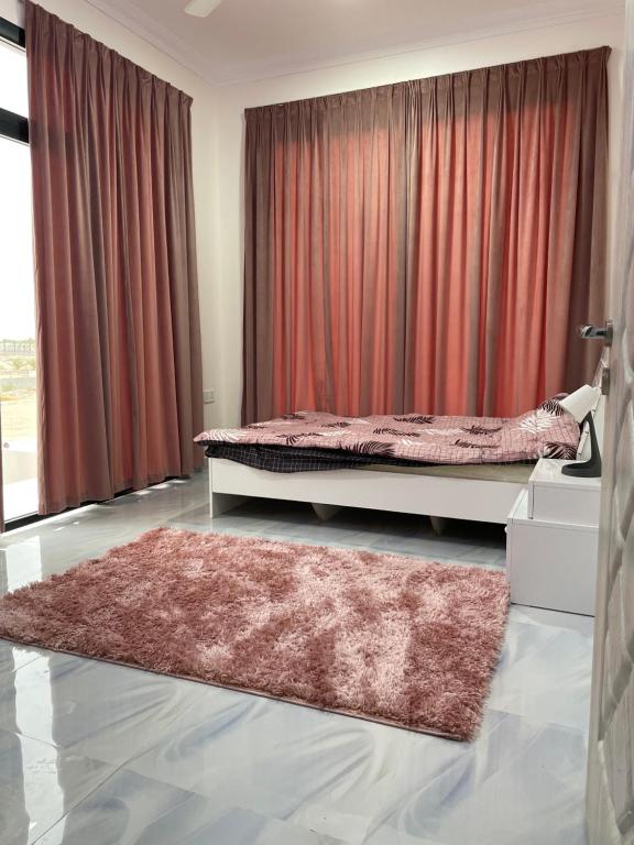 1 dormitorio con 1 cama con cortinas rojas y alfombra en شالية الفضائل en Barka