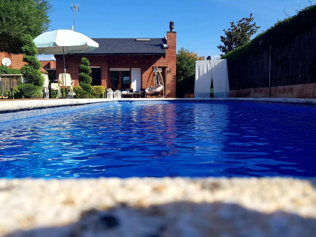 una piscina frente a una casa con sombrilla en Ca LaMari en Vidreres