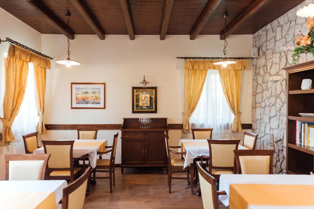 a dining room with tables and chairs and a stone wall at Hotel & Restaurant Pahor in Doberdò del Lago