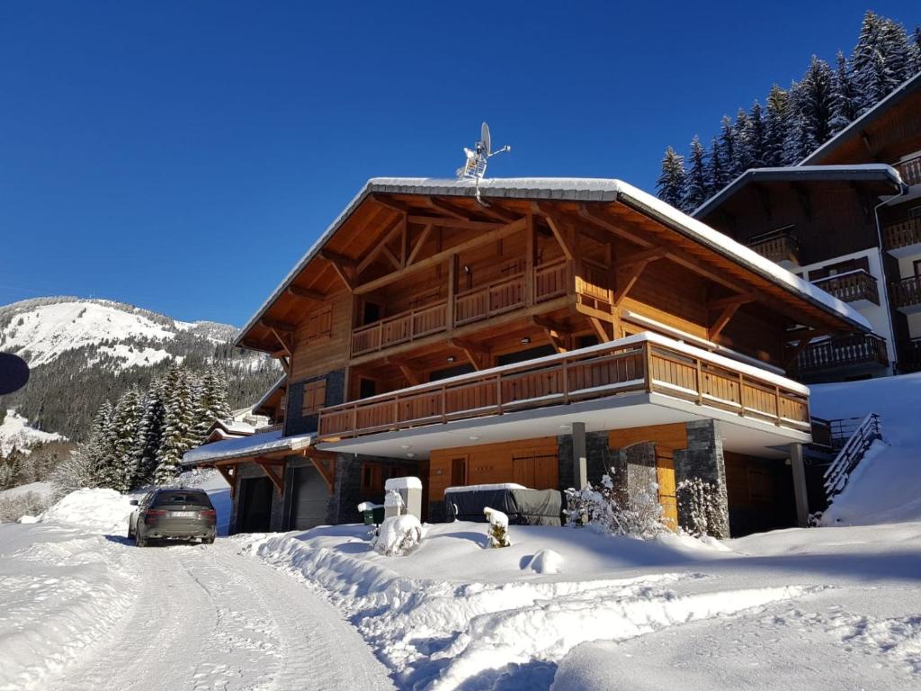 un lodge de ski dans la neige avec une voiture garée devant dans l'établissement Chalet CLEMALOU 14-16 personnes avec jacuzzi, à Châtel