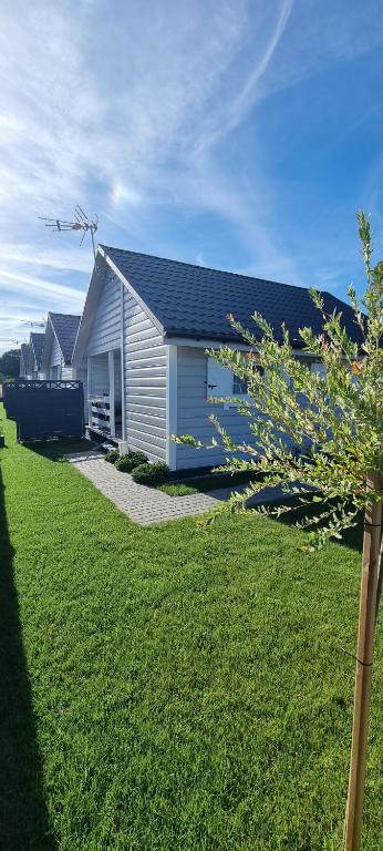 une maison blanche avec une pelouse devant elle dans l'établissement domki letniskowe ŚWIĘTY SPOKÓJ, à Rusinowo