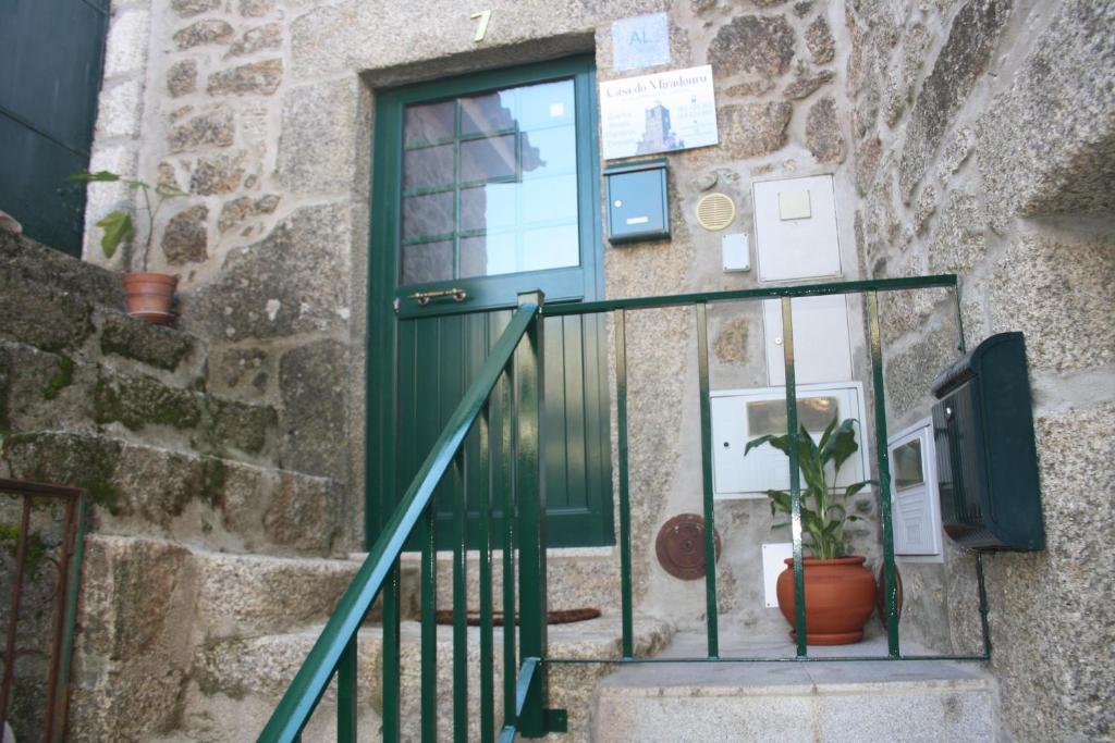 a green door on a stone building with a potted plant at Casa do Miradouro in Monsanto