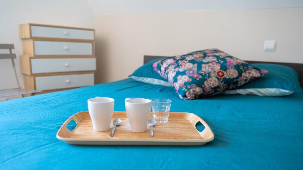 a tray with two cups and a glass on a bed at SECRET MAMA with Aircon 150 meters from parking Rapp in Colmar