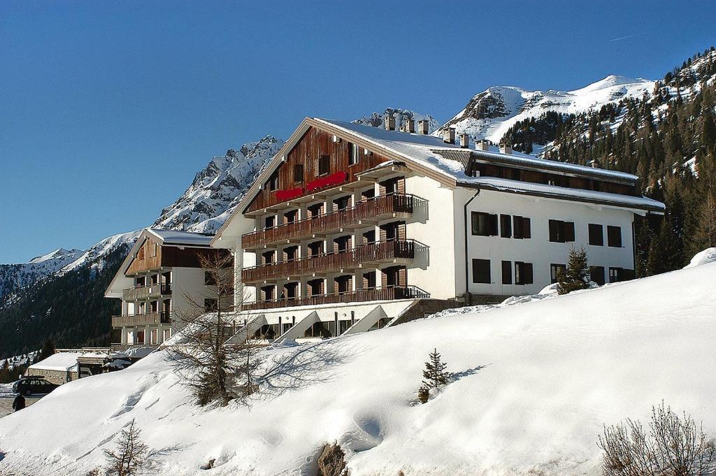 ein Gebäude auf einem verschneiten Hügel mit einem Berg in der Unterkunft Appartamento AB in Passo San Pellegrino