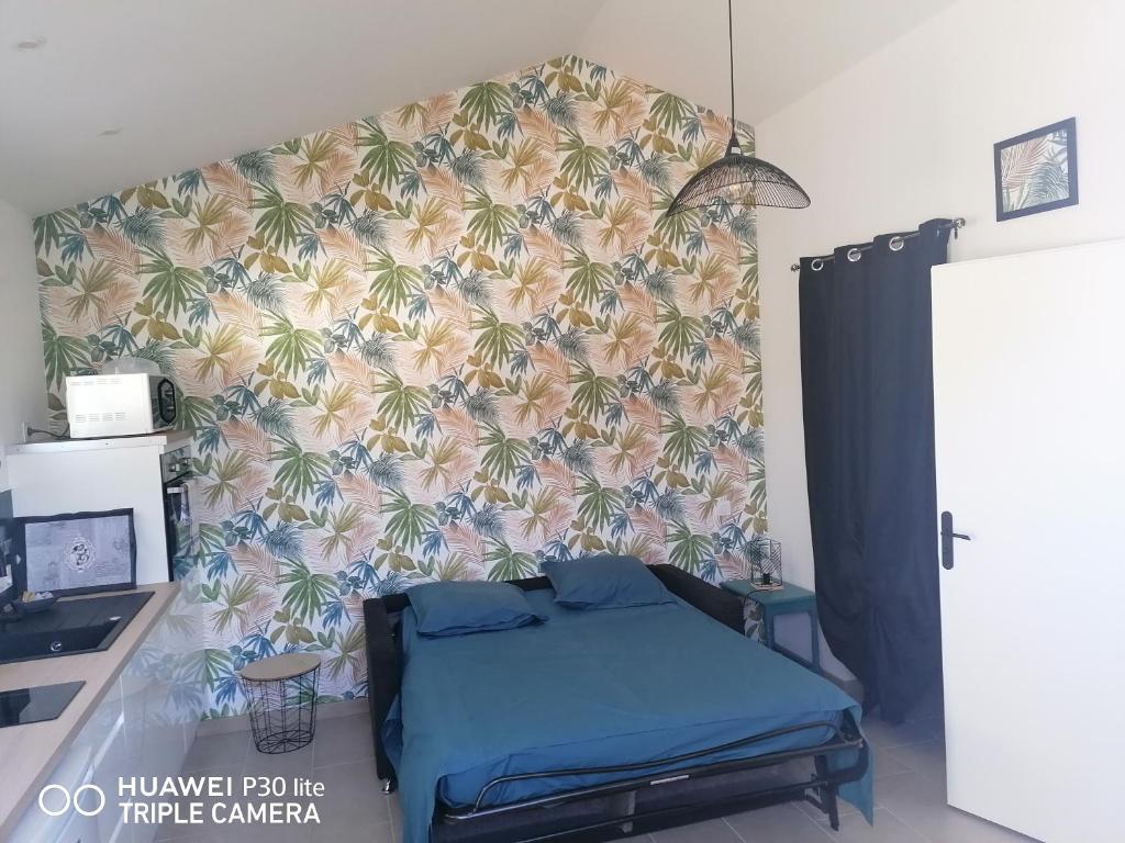 uma cama num quarto com um papel de parede com palmeiras em Studio em Challans