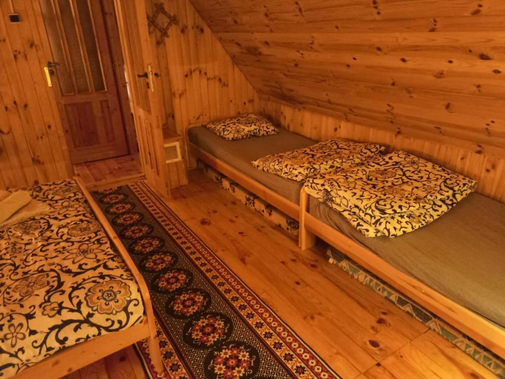DOMEK LETNISKOWY MYSCÓWKA في Krempna: غرفة بسريرين في كابينة خشبية