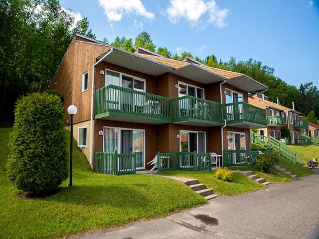 a large house with green balconies on a street at Chalets Condos sur le Fjord in LʼAnse-Saint-Jean