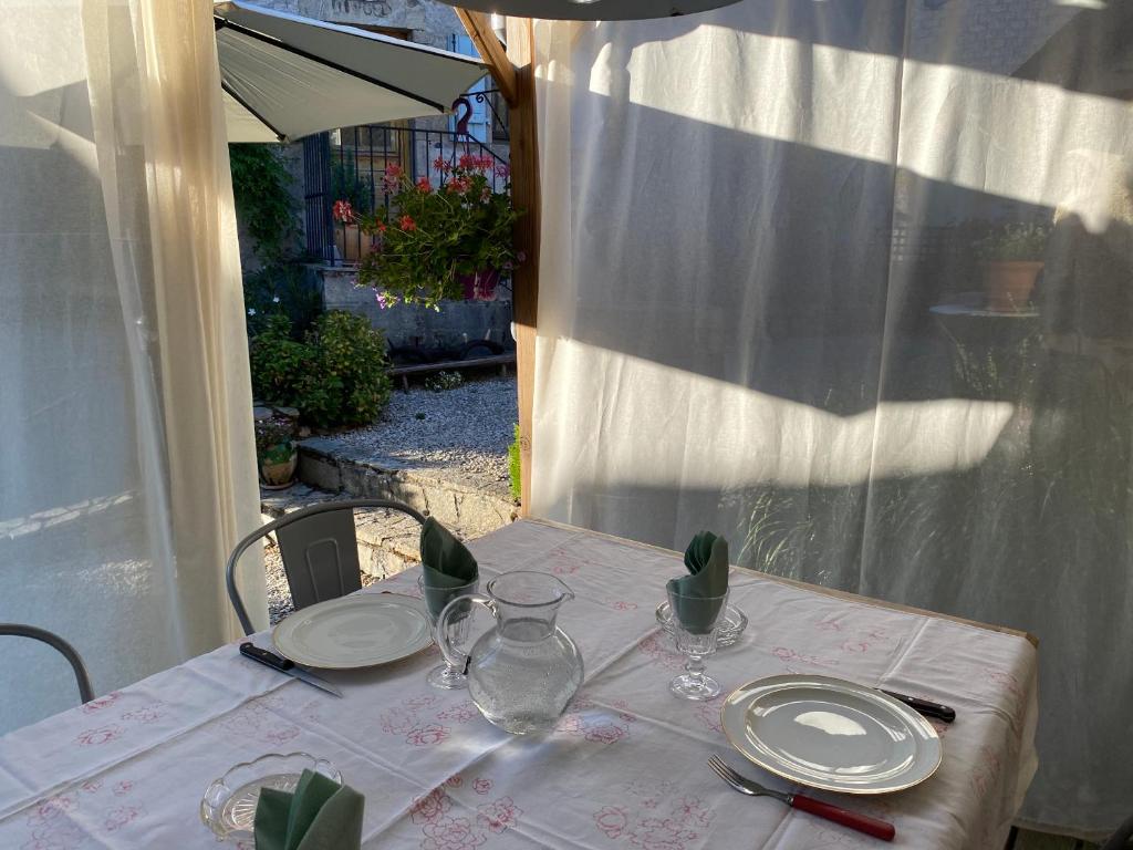 a table with plates and glasses on top of it at Gîte Maison Maitri in Forgès