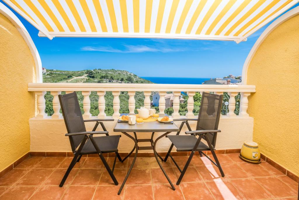 einen Tisch und Stühle auf einem Balkon mit Meerblick in der Unterkunft Casa Frederyk in Cumbre del Sol