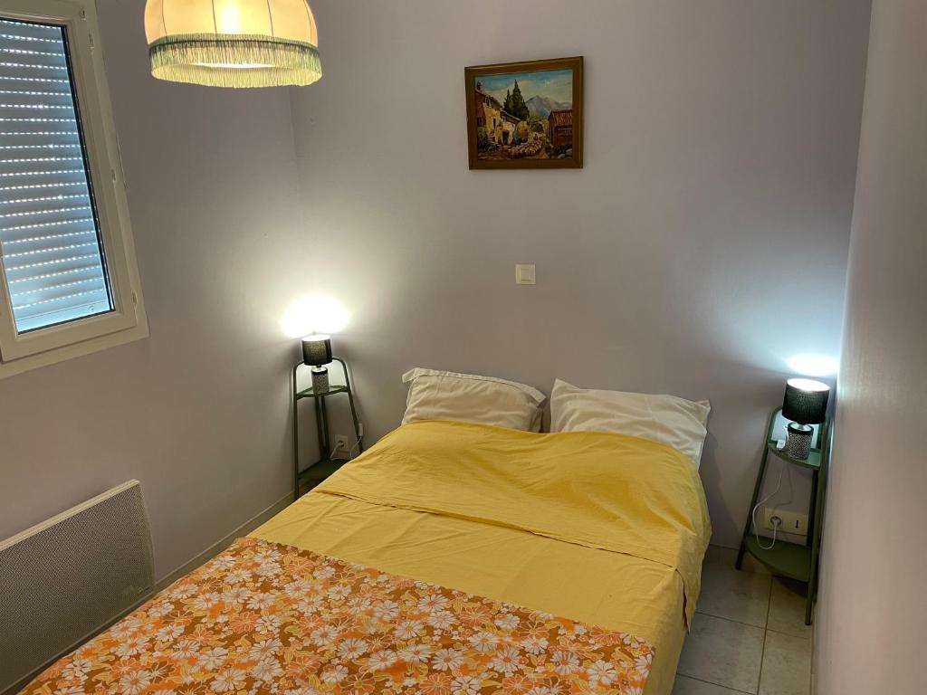 a bedroom with a bed with yellow sheets and two lamps at Gîte ylangylang in Saint-Paul-le-Jeune