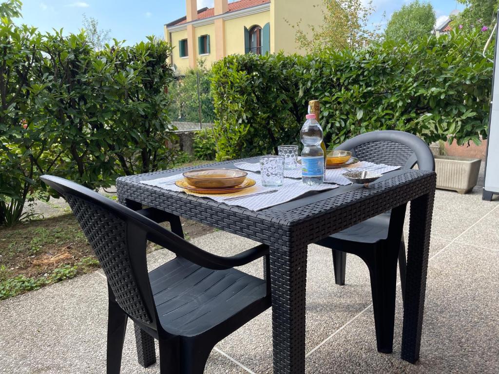 - une table en osier noir avec une bouteille et deux chaises dans l'établissement ONLY THE BEST 5 La tua Suite tra Venezia e Treviso, à San Trovaso