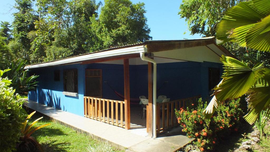 a blue house with a porch in a garden at Cabinas Caribe Luna in Cahuita