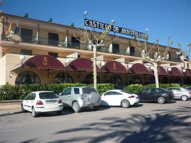 un groupe de voitures garées sur un parking devant un bâtiment dans l'établissement Hotel Castillo de Montemayor, à Montemayor