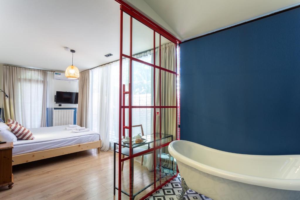 baño con bañera, cama y pared azul en Shota Rustaveli Aparthotel, en Tiflis