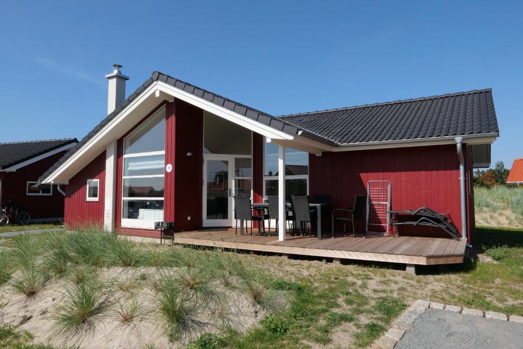 uma casa vermelha com um deque de madeira em frente em Resort 2 Sea Lodge C 73 em Grossenbrode