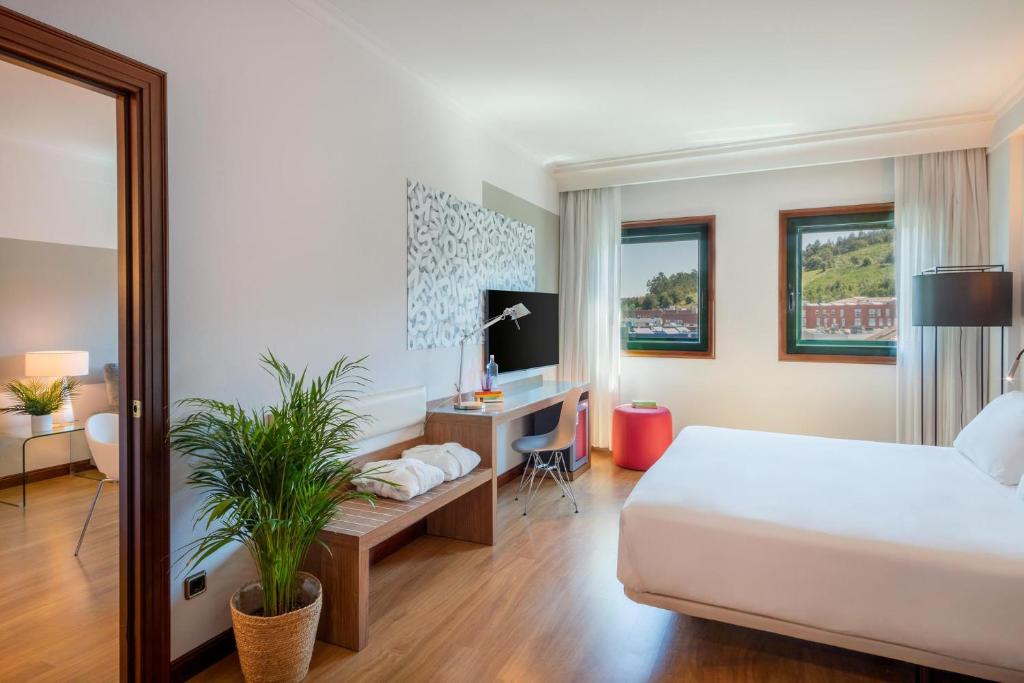 1 dormitorio con 1 cama y escritorio con ordenador en Hotel Santiago Plaza Affiliated by Meliá, en Santiago de Compostela