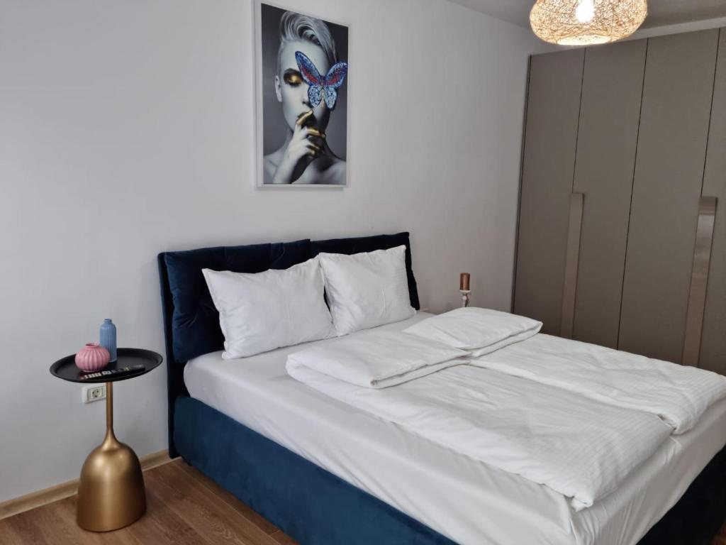 um quarto com uma cama grande com lençóis brancos e uma mesa em Sasu Apartment em Timisoara