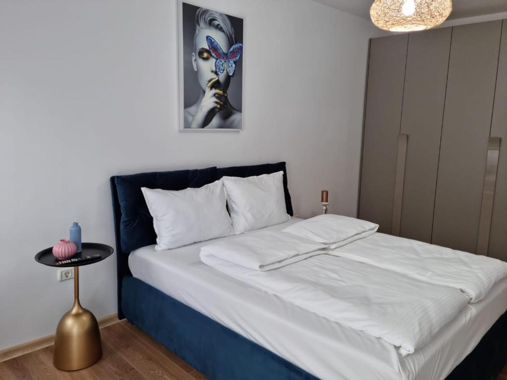 a bedroom with a large bed with white sheets and a table at Sasu Apartment in Timişoara