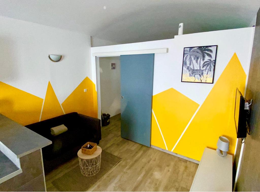 Location T1 Bis (RdC) / Emplacement Ideal في لو بوزين: غرفة معيشة مع جدران ملونة وأريكة