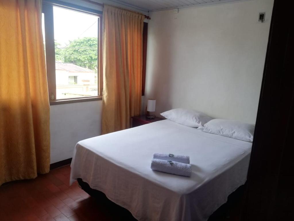 a bedroom with a white bed with a window at Tucuma Casa Hotel in Leticia