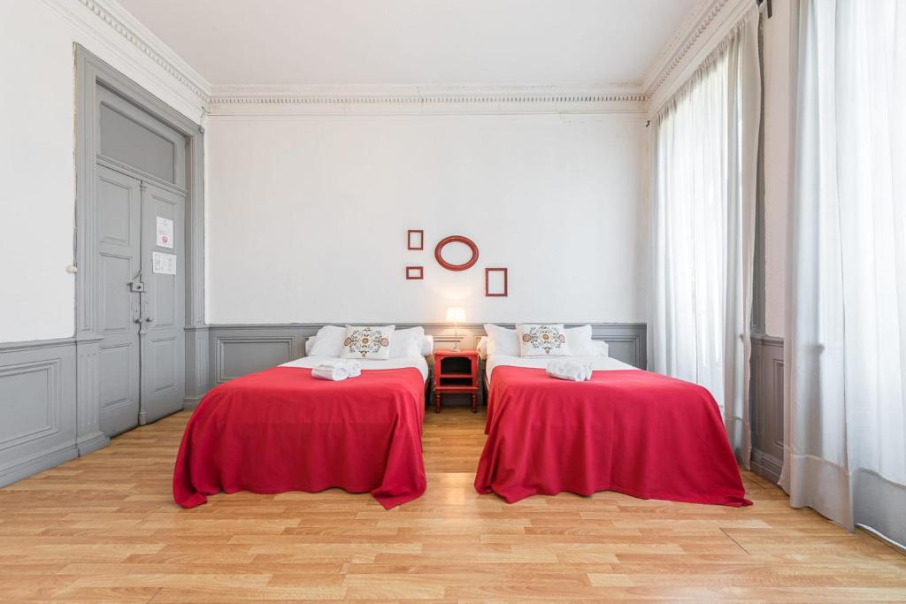 two beds in a white room with red sheets at GuestReady - Centenary Oporto Cosy - Room 3 in Porto