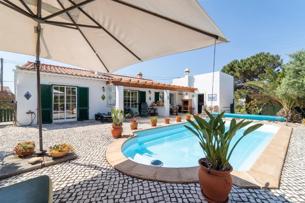 uma villa com uma piscina e um guarda-sol em Bliss Villa em Aljezur