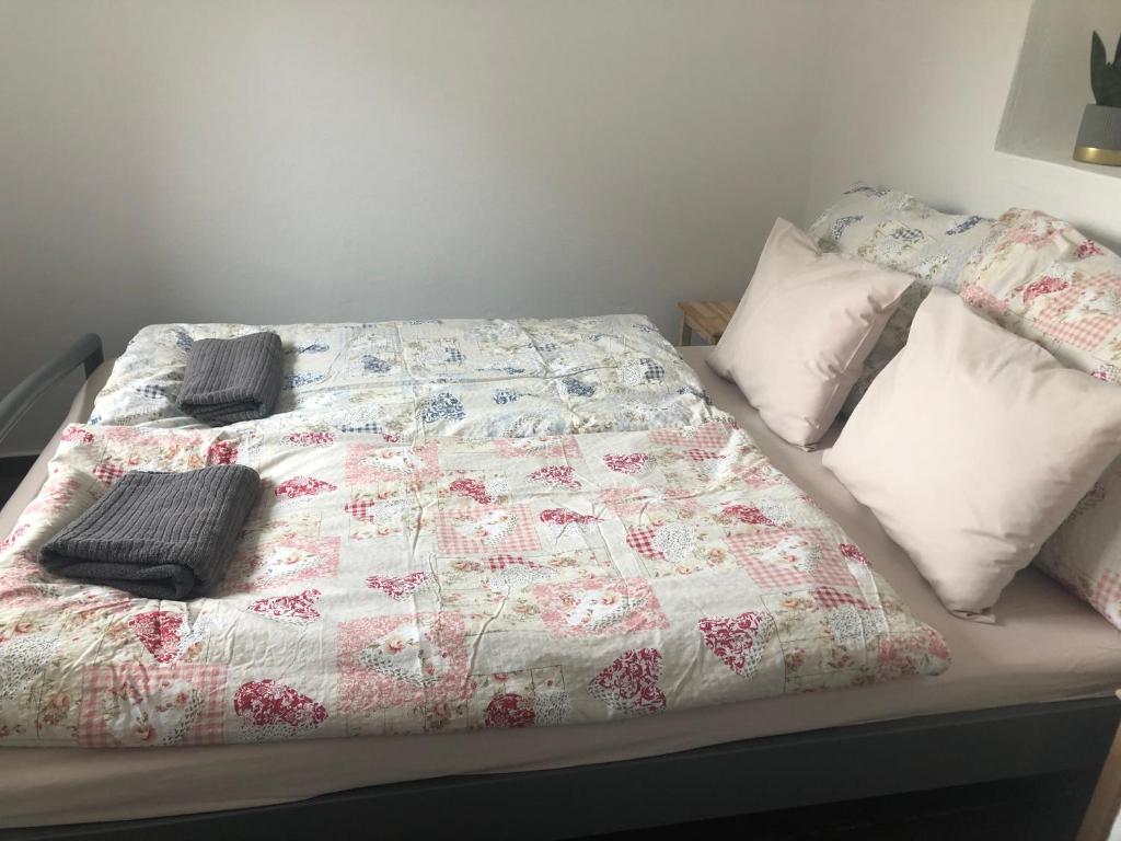 ein Bett mit einer Decke und Kissen darauf in der Unterkunft Dália apartman Gyömrő in Gyömrő