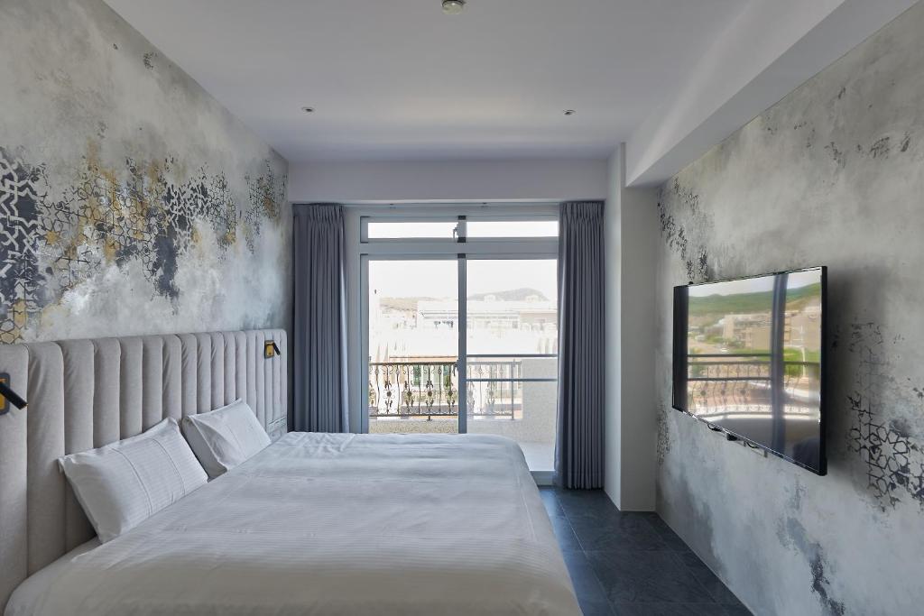 - une chambre avec un lit et une télévision murale dans l'établissement 芙蘿拉萃旅, à Taïtung