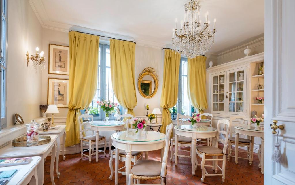 uma sala de jantar com mesas e cadeiras e um lustre em Les Quatre Dauphins em Aix-en-Provence