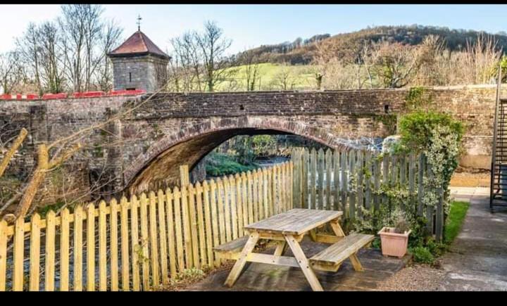 a wooden picnic table in front of a stone bridge at Glan-Yr-afon cottage two bedrooms in Sennybridge