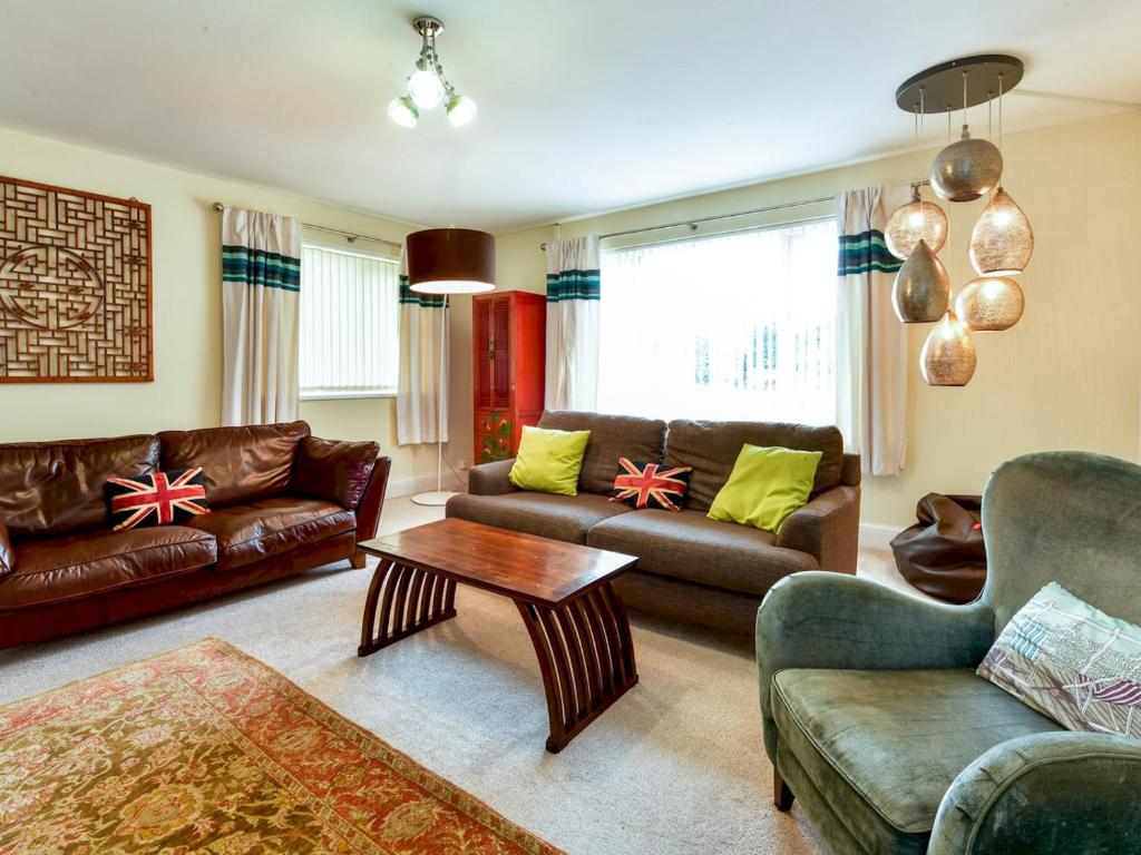 a living room with leather couches and a table at Pass the Keys Spacious 4 Bedroom home with Parking Garden in Barry