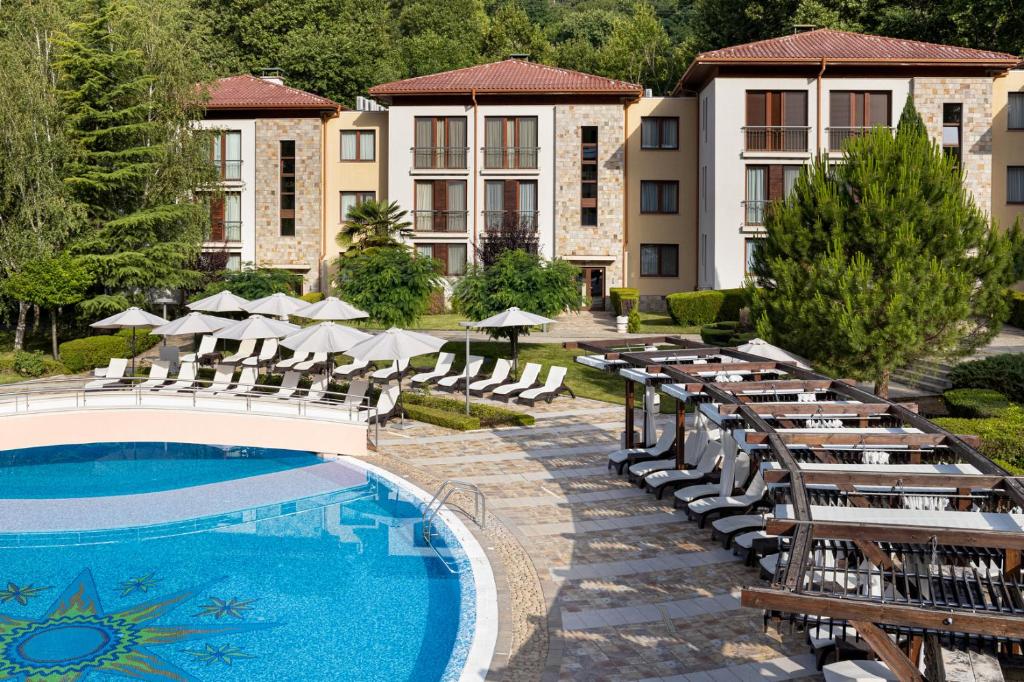 un complexe avec une piscine, des chaises et un bâtiment dans l'établissement Pirin Park Hotel, à Sandanski