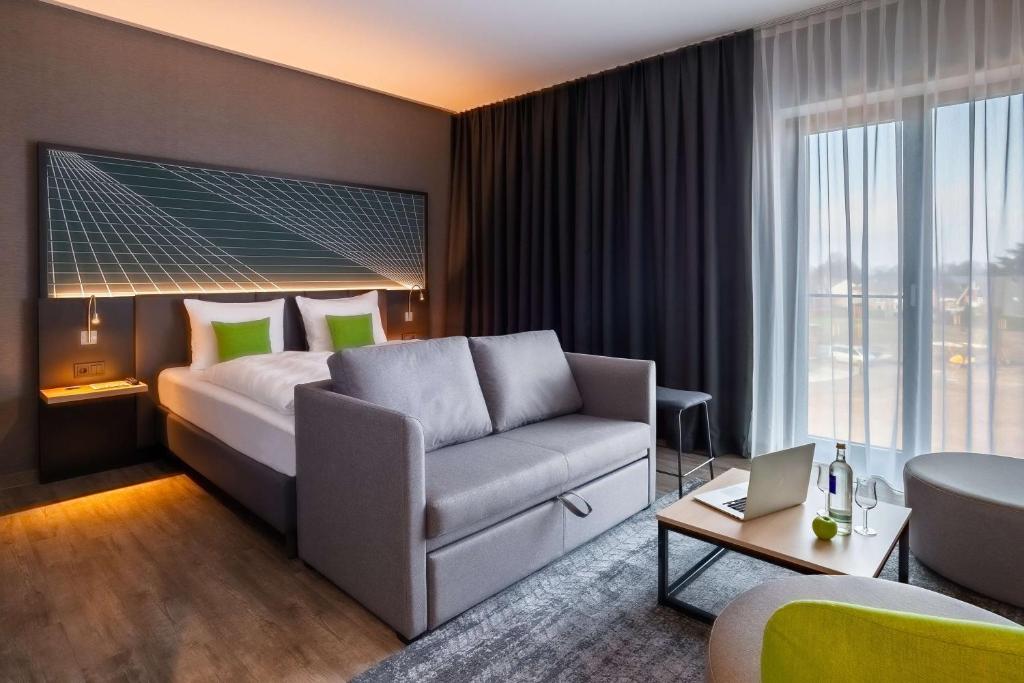 a hotel room with a bed and a couch at elaya hotel kevelaer in Kevelaer
