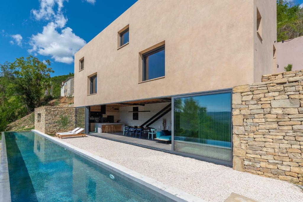 a house with a swimming pool next to a stone wall at Villa Terra Motovun in Motovun
