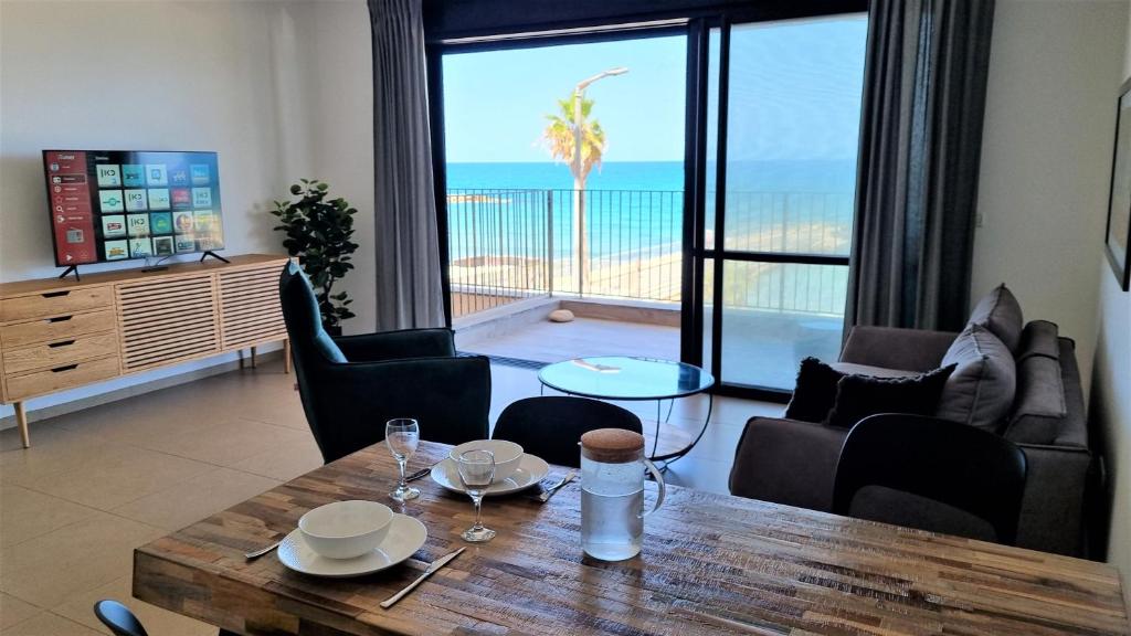 a living room with a table and a view of the ocean at PORT CITY HAIFA - Beach front luxury apartment - MAMAK in Haifa