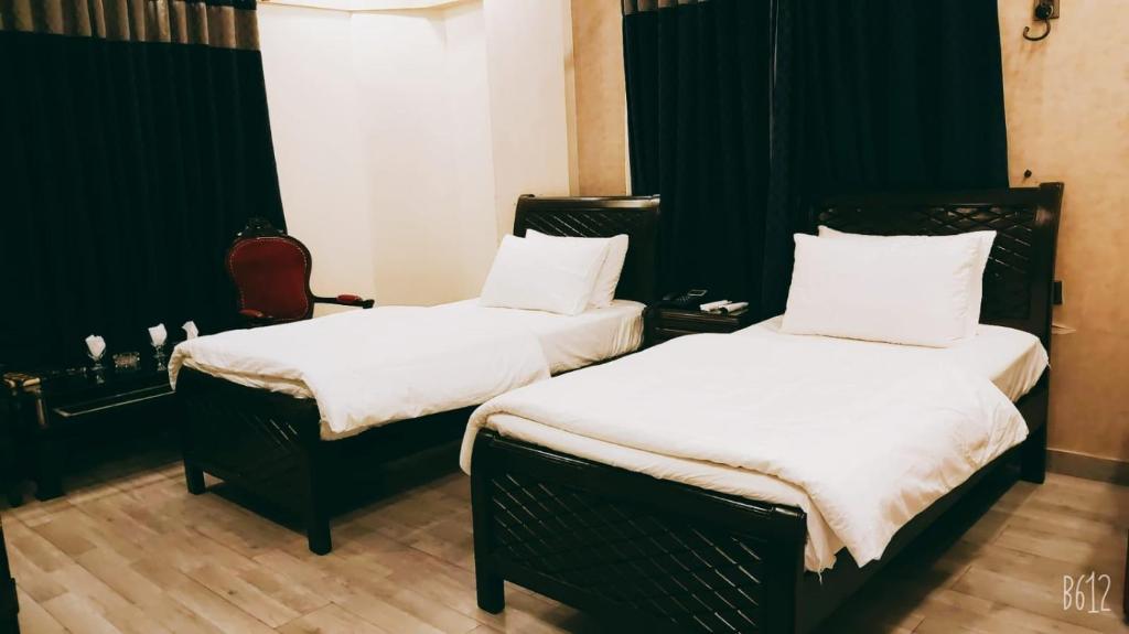 Habitación con 2 camas en blanco y negro en The Elet Business Hotel en Karachi