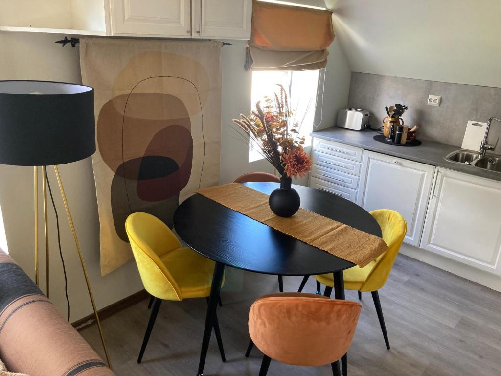 a kitchen with a black table and yellow chairs at Downtown Historical House with Renovated apartments in Ålesund