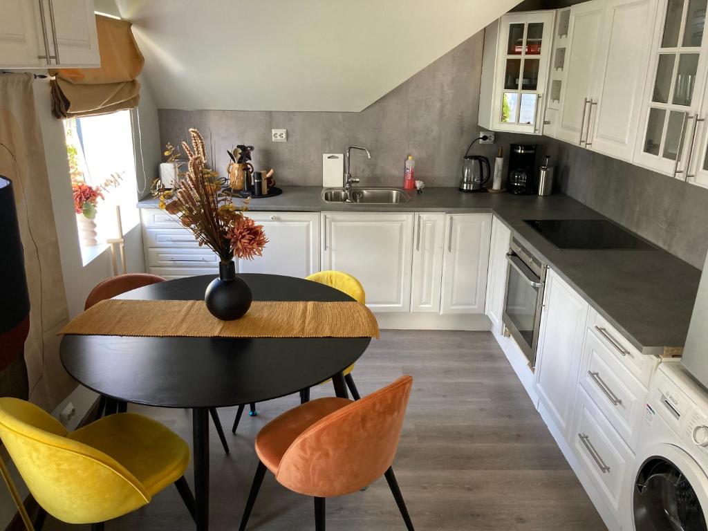 a kitchen with a black table and yellow chairs at Downtown Historical House with Renovated apartments in Ålesund