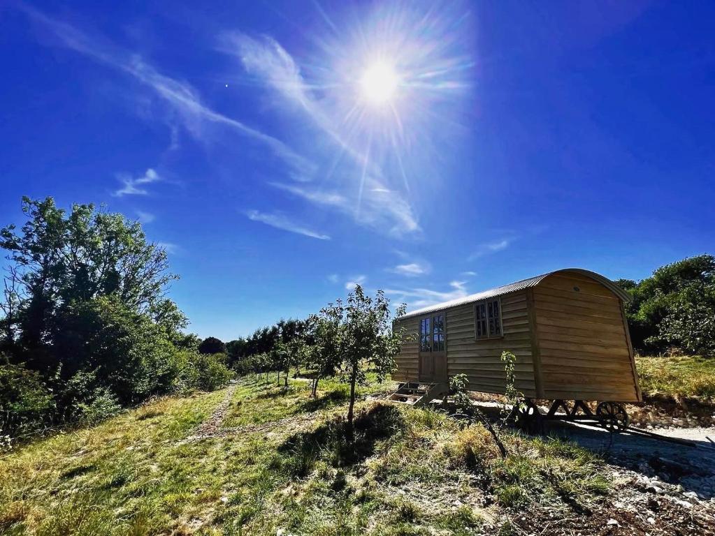 a wooden cabin on a hill with the sun in the sky at Robins Retreat - orchard with hot tub - see extras in Alfriston