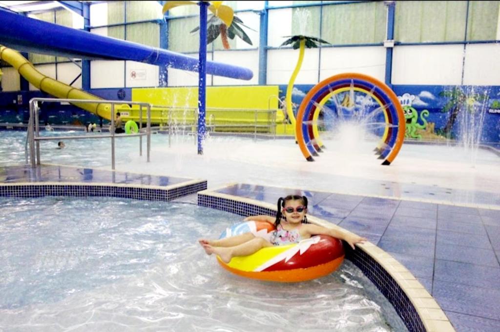 a woman laying on a raft in a swimming pool at Golden Palm Getaway's PG143 in Skegness